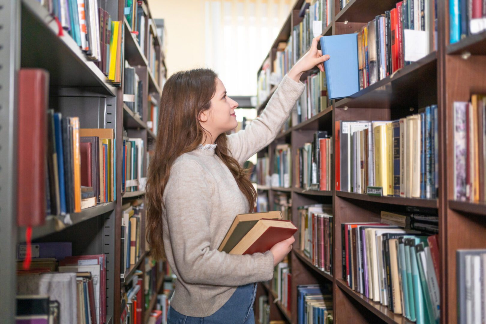Woman selecting book in library aisle