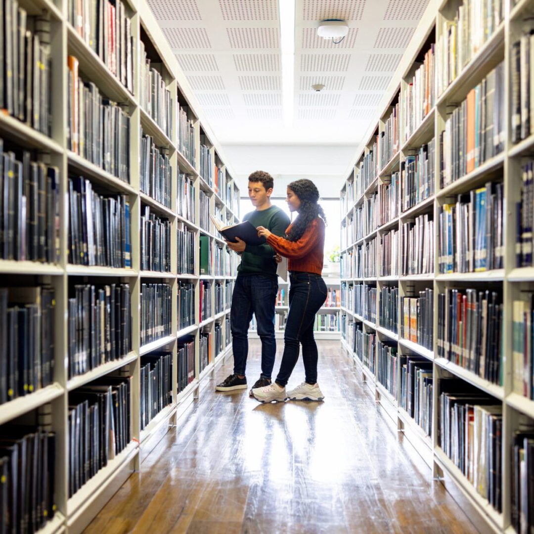 People reading books in library aisle